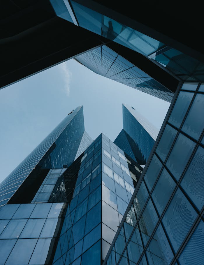 Low angle view of futuristic skyscrapers with glass facades against a clear blue sky.